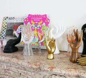 Tula Pink's mantle features a collection of hand statues that hold up two of her books.