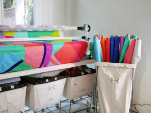 A quilt featuring Tula Pink's solid fabric collection is being stitched on her long arm quilting machine.