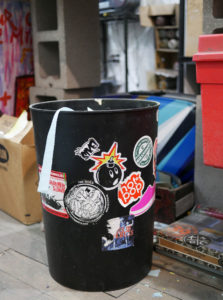 A garbage can is covered in Sike Style stickers in Phil Shafer's studio.