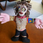 A handmade doll featuring a heavily beaded face.