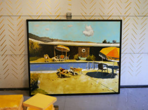 A Seth Smith painting of a retro pool scene leans agains a garage door carefully decorated with gold dashes.