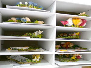 A file cabinet holds stacks of flower wreaths waiting to be shipped.