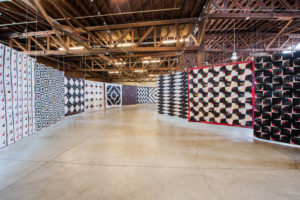 A corridor or Luke's quilts flow through an exhibition space.
