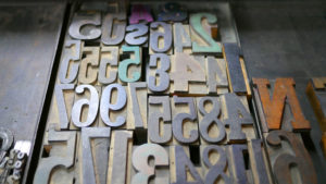 A tray full of letterpress numbers are tinted with the colors of recently used ink.