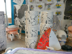 Unglazed mugs sit next to a color sample of one of Momoko's moth pieces.