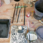 Paintbrushes and glazes await their turn on Momoko's studio workspace.