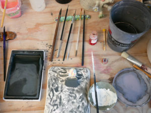 Paintbrushes and glazes await their turn on Momoko's studio workspace.